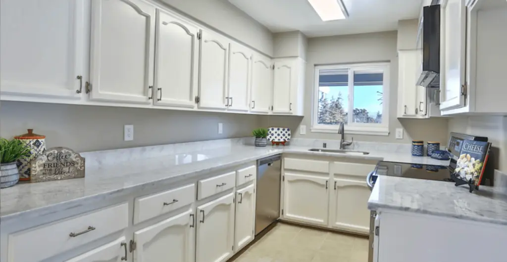 Modern kitchen with white cabinets and marble countertops.