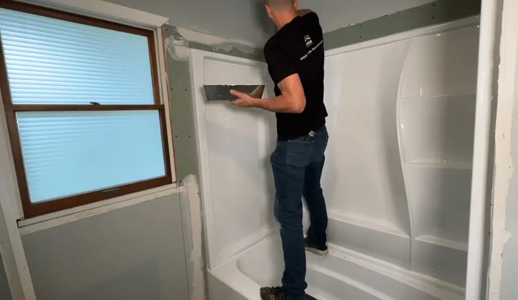 A person works on installing drywall around a bathtub during a bathroom remodel. Start your bathroom transformation today—contact us for a timeline and free consultation!